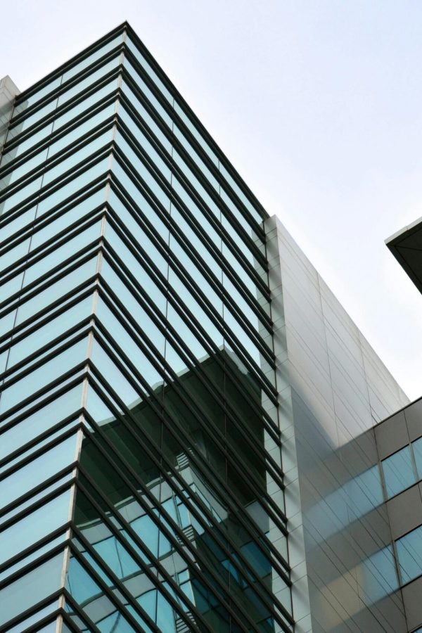 Low angle view of a modern skyscraper with glass facade reflecting the sky.