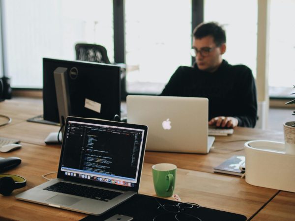 A web developer working on code in a modern office setting with multiple devices.